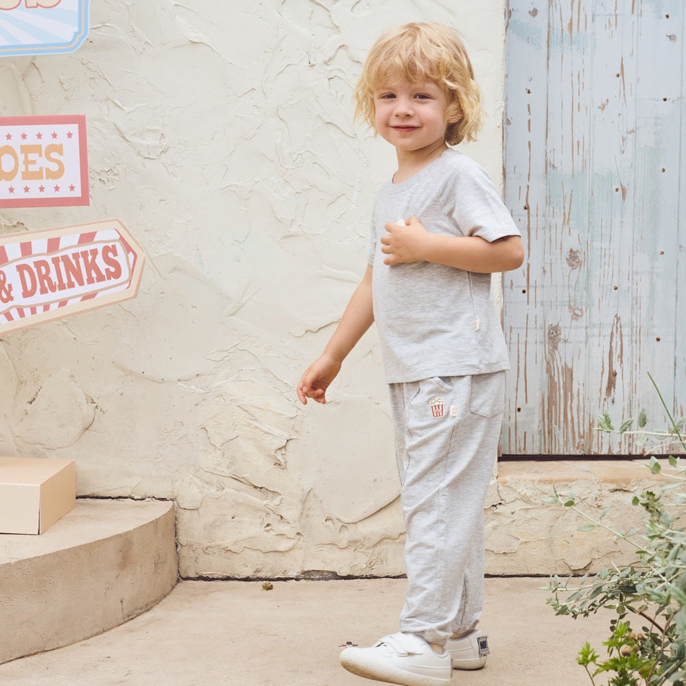 Child standing outdoors against a textured wall with signs.