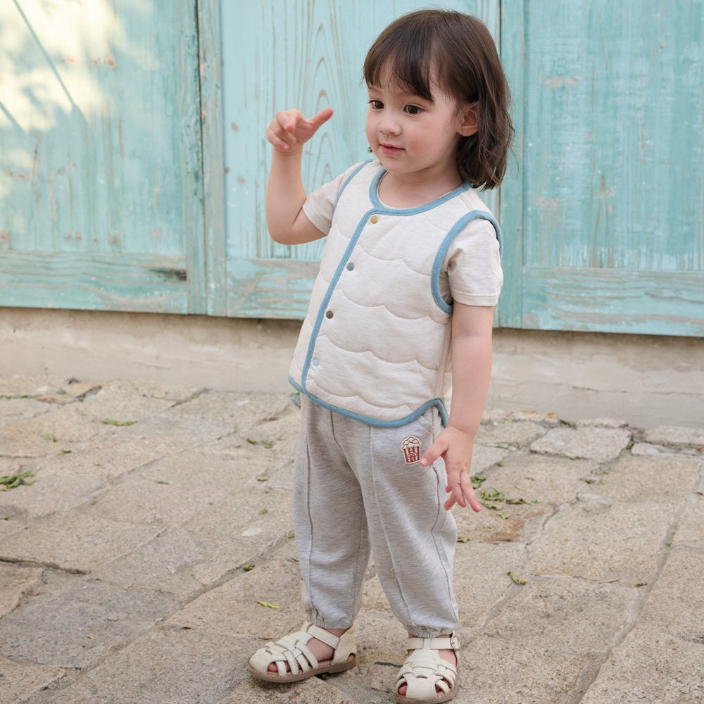 Child standing on a stone path in front of a light blue wooden gate