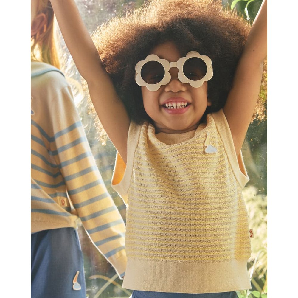 Petite Revery Cotton Knit Sleeveless Vest Mellow Yellow worn by a happy toddler with arms raised.