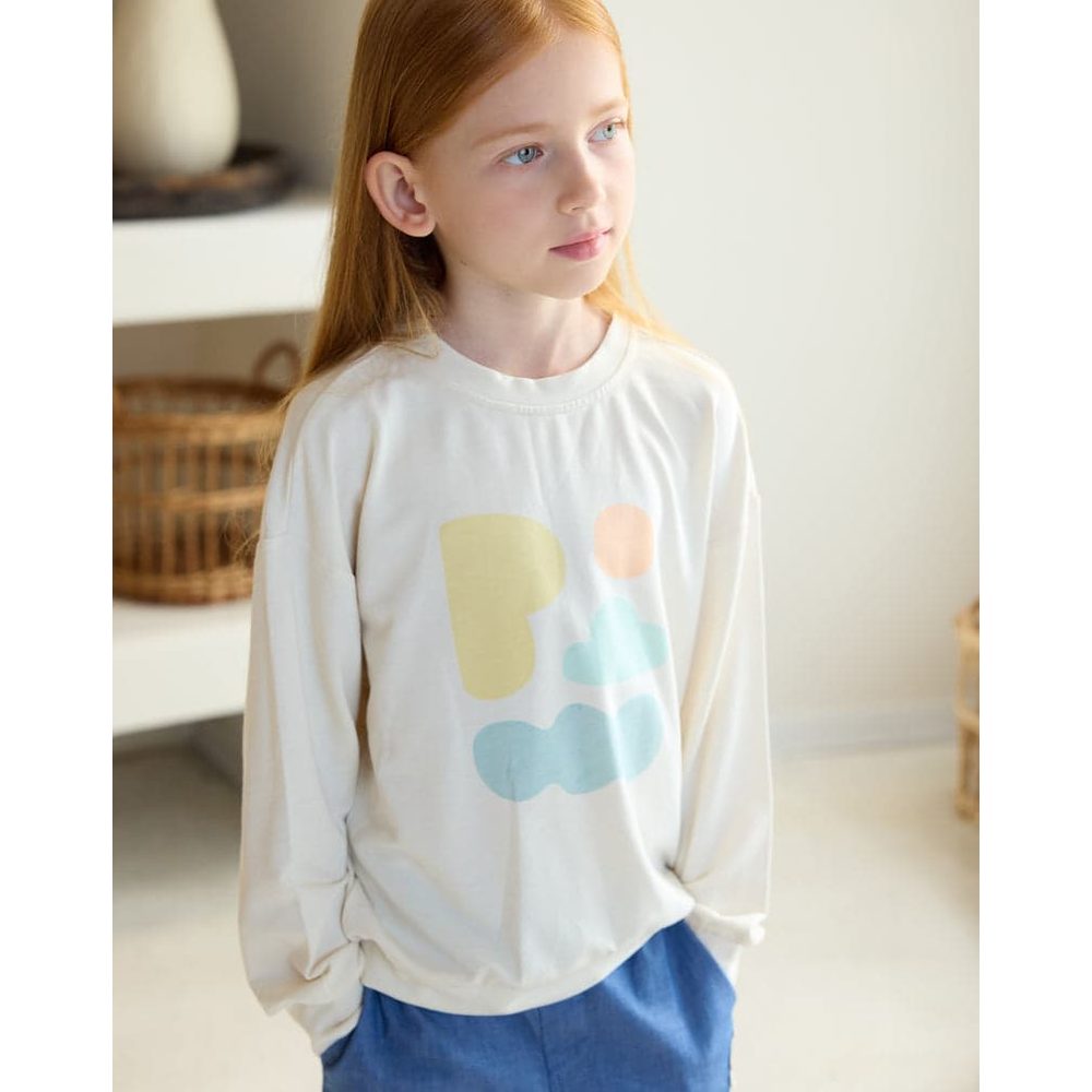 Petite Revery French Terry Drop Shoulder Long Sleeve Sweatshirt Jet Stream, cream with pastel shapes, girl stands with hands in pockets.