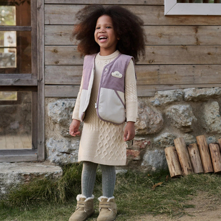 Petite Revery down vest in cloud lilac-gray worn over cream knit dress with tan fur-lined boots.