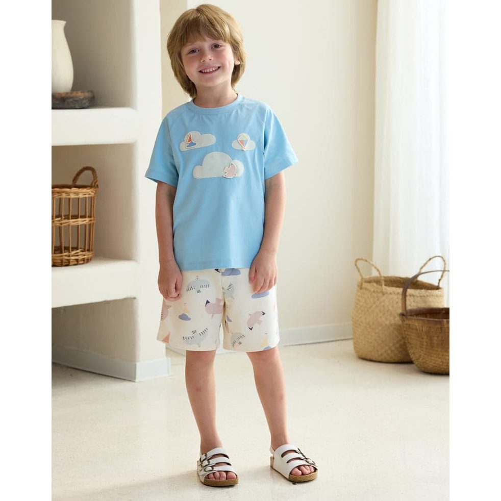 Petite Revery Forget-Me-Not quick-dry cotton raglan tee worn by a smiling toddler in a sky-blue shirt with cloud graphics.