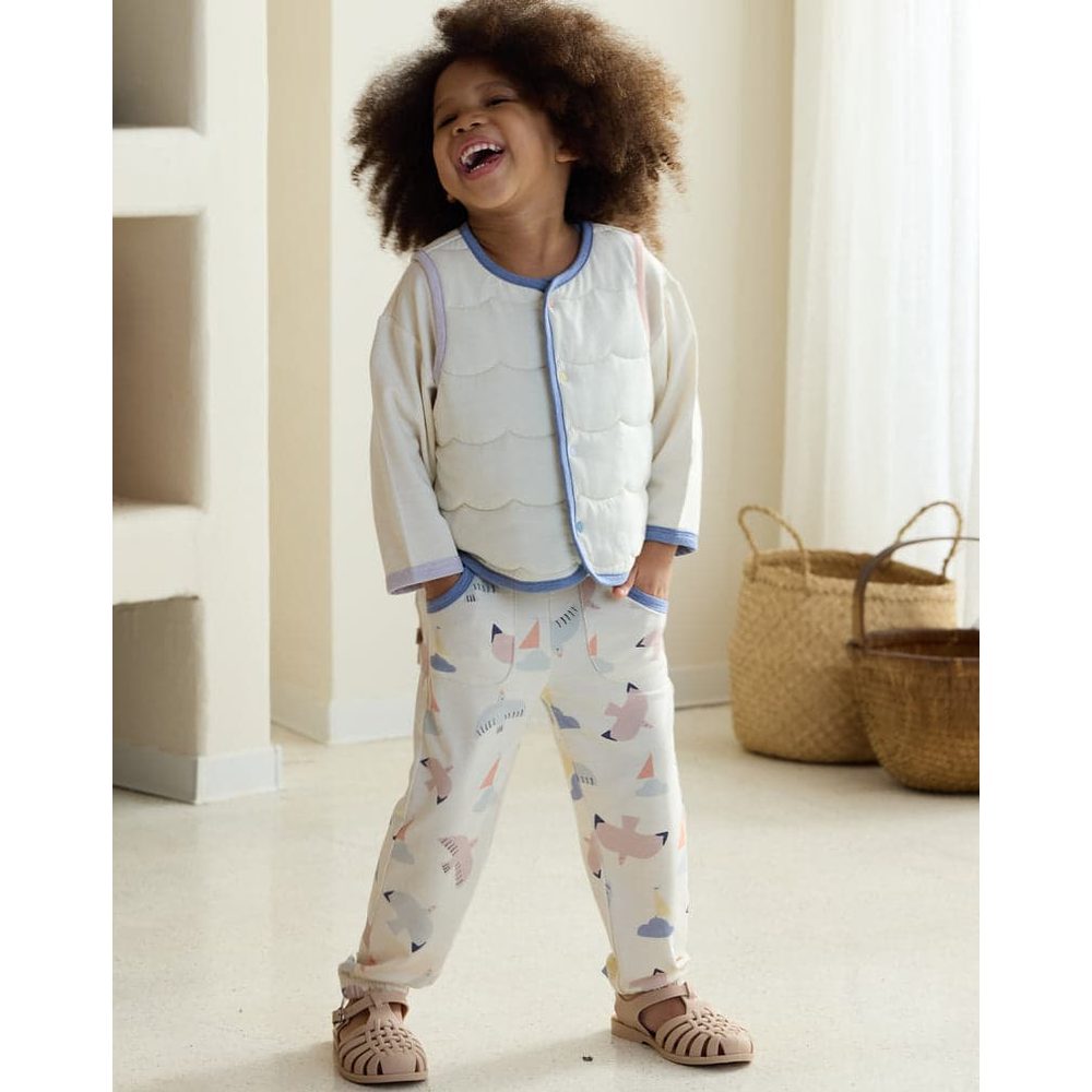 Petite Revery Quilted Sea Vest Jet Stream worn by giggling toddler in pastel pajamas with blue trim.