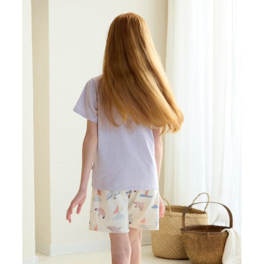 Petite Revery Short Sleeve Tee Lavender Blue for baby; back view of a girl walking in lavender tee with pastel printed shorts.