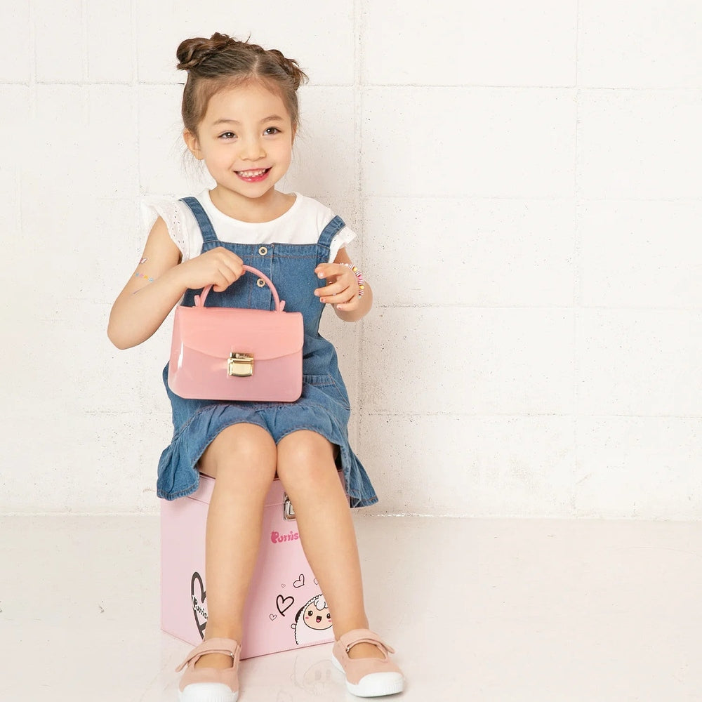 Puttisu Charming Bag for kids, pink mini purse with gold clasp carried by a smiling girl