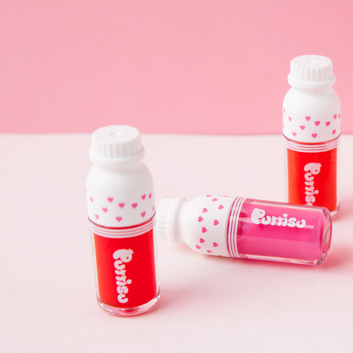 PUTTISU Puttisu Juicy Lip Gloss #01 Red Ruby, three lip gloss bottles with red and pink gloss and white caps featuring hearts