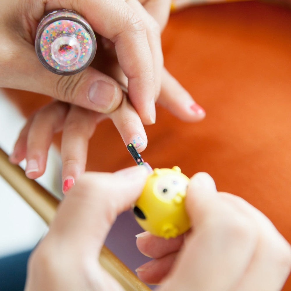 PUTTISU Pangpang Nail Art Kit Pink Snow; glitter bottle and a child painting a yellow nail charm