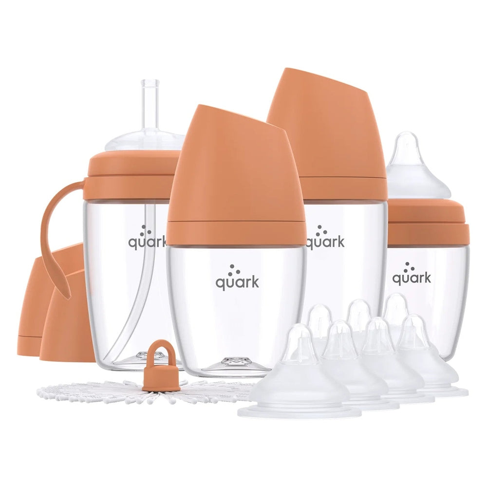 Quark Buubibottle Hybrid Feeding Bundle: four clear baby bottles with orange caps and assorted nipples ready for feeding.