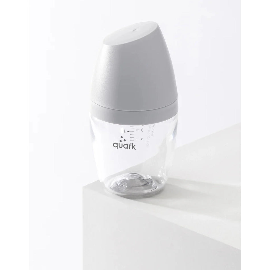 Quark Buubibottle Mini Hybrid feeding bottle, clear body with gray cap, upright on white surface showing measurement marks.