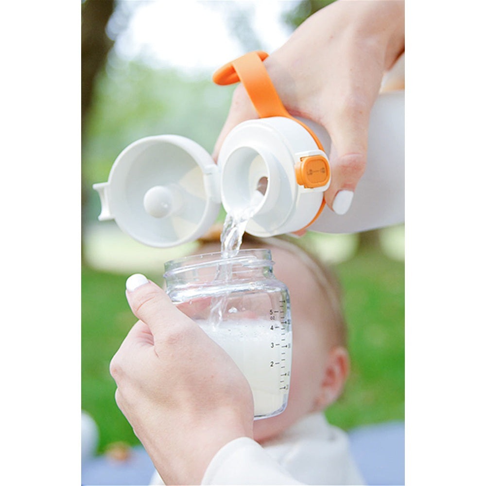 QUARK Buubibottle smart portable milk warmer with orange strap pouring milk into a baby bottle