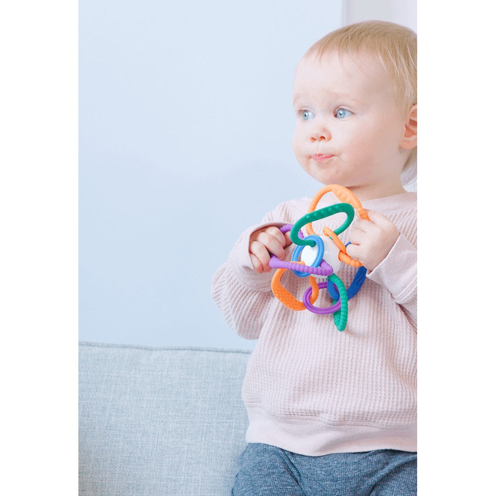 Quark Thiingy sensory teether with colorful silicone rings held by a baby