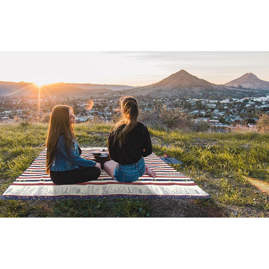 Ray Star 79x79 picnic blanket, red and blue striped, sandproof and waterproof outdoor mat; two people sitting on grass.