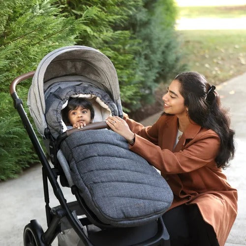 Romer Tura Winter Kit cover and gloves on a stroller; warm grey fabric keeps baby cozy as mom adjusts.