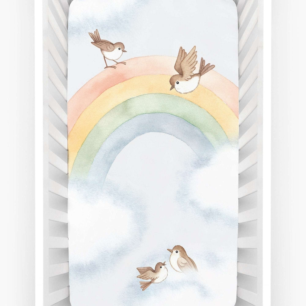 Rookie Humans crib sheet in cotton sateen with pastel rainbow and four birds on clouds