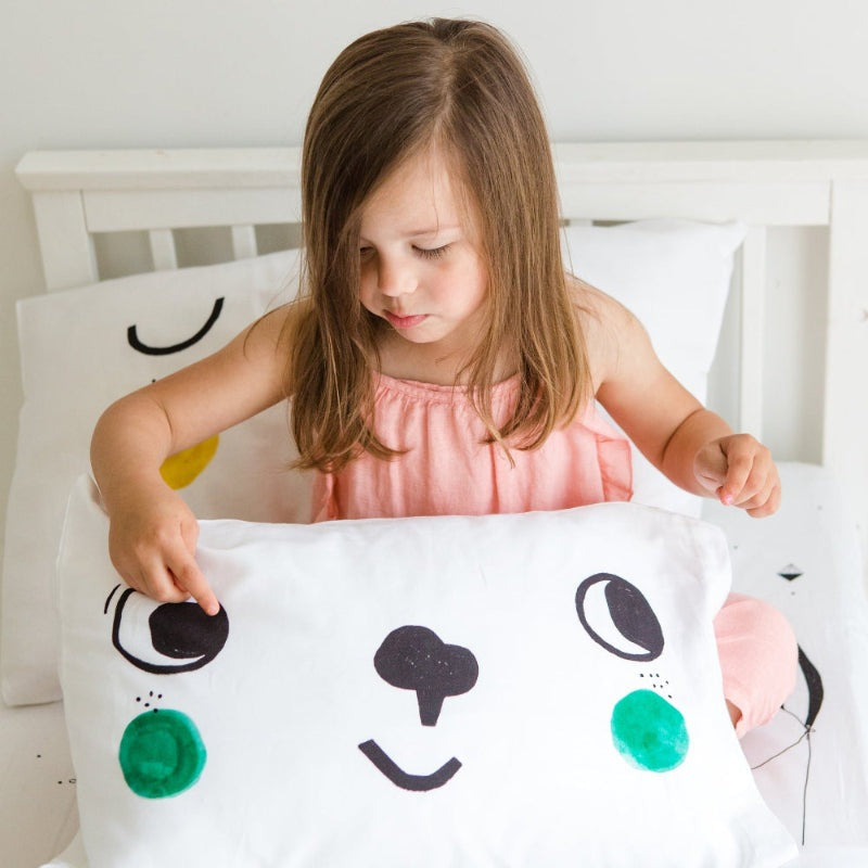 Rookie Humans Standard Pillowcases 2-Pack; white with a cute facial design, girl in pink holding one