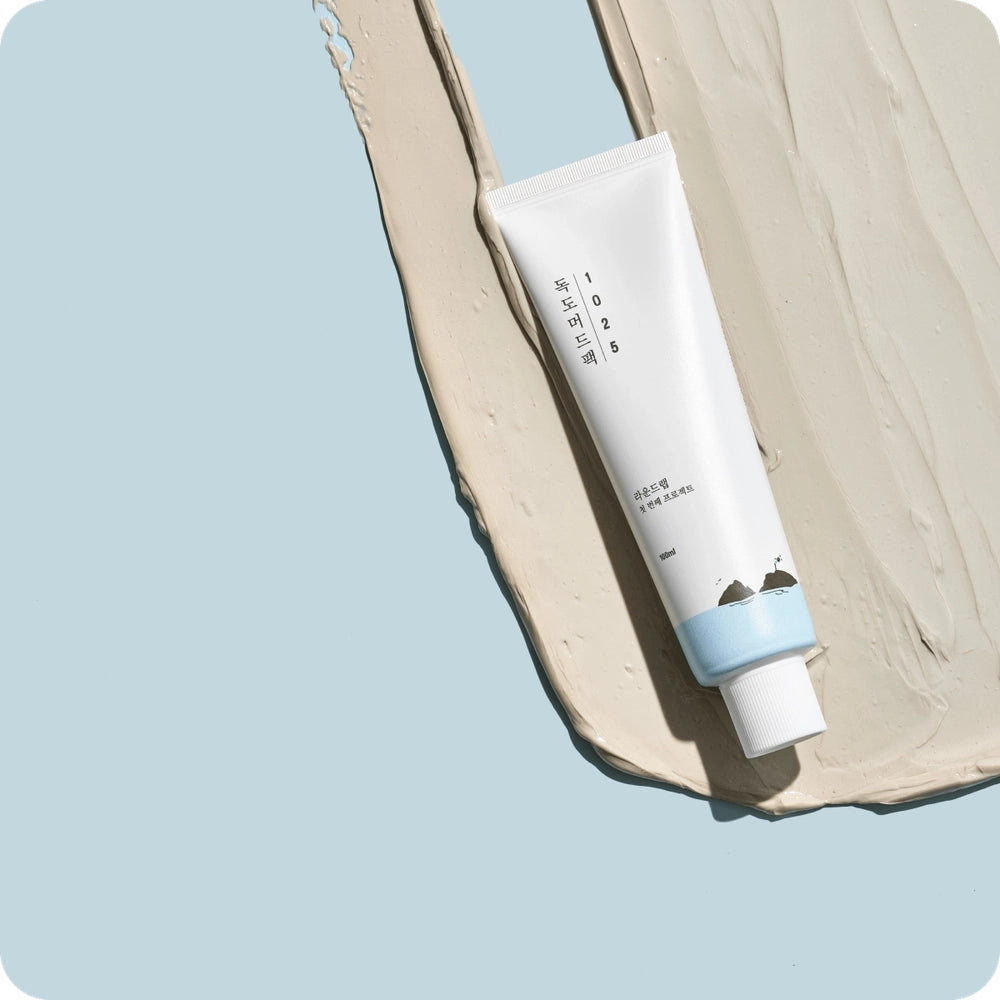 Round Lab 1025 Dokdo Mud Pack 100 ml white tube with light blue cap on beige cream smear