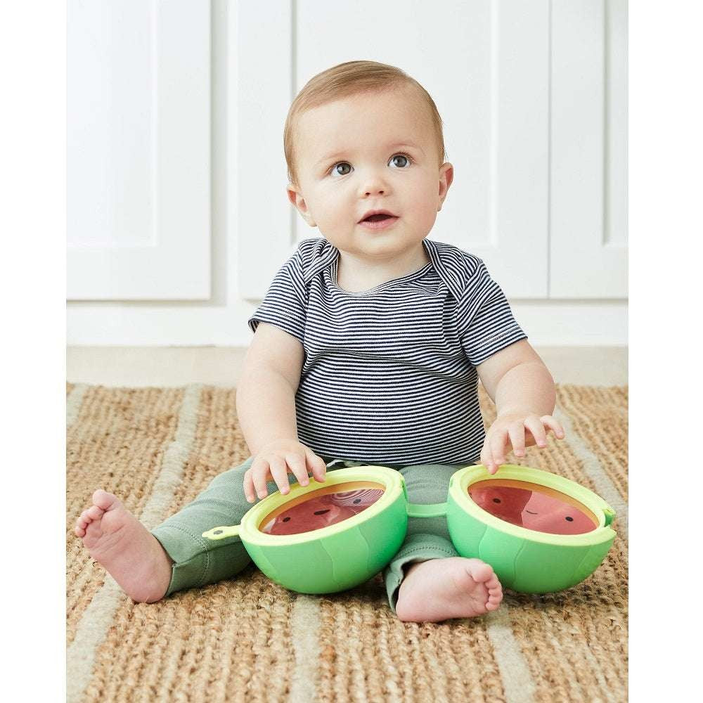 Skip Hop Farmstand Melon Drum baby toy; two green melon drums with red interiors beside a seated baby.