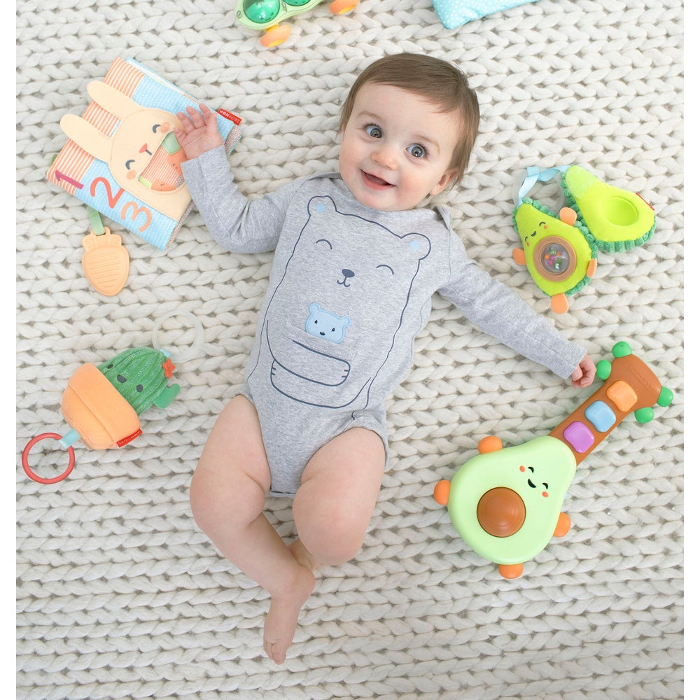 Skip Hop Farmstand Pod Squad Car toy in lime green with orange accents on a soft rug