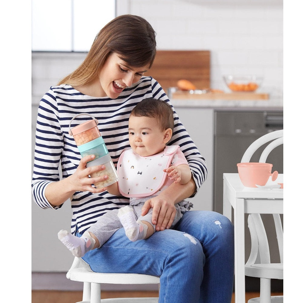 Skip Hop formula-to-food containers set; four pastel stackable containers with peach, mint, and gray lids.