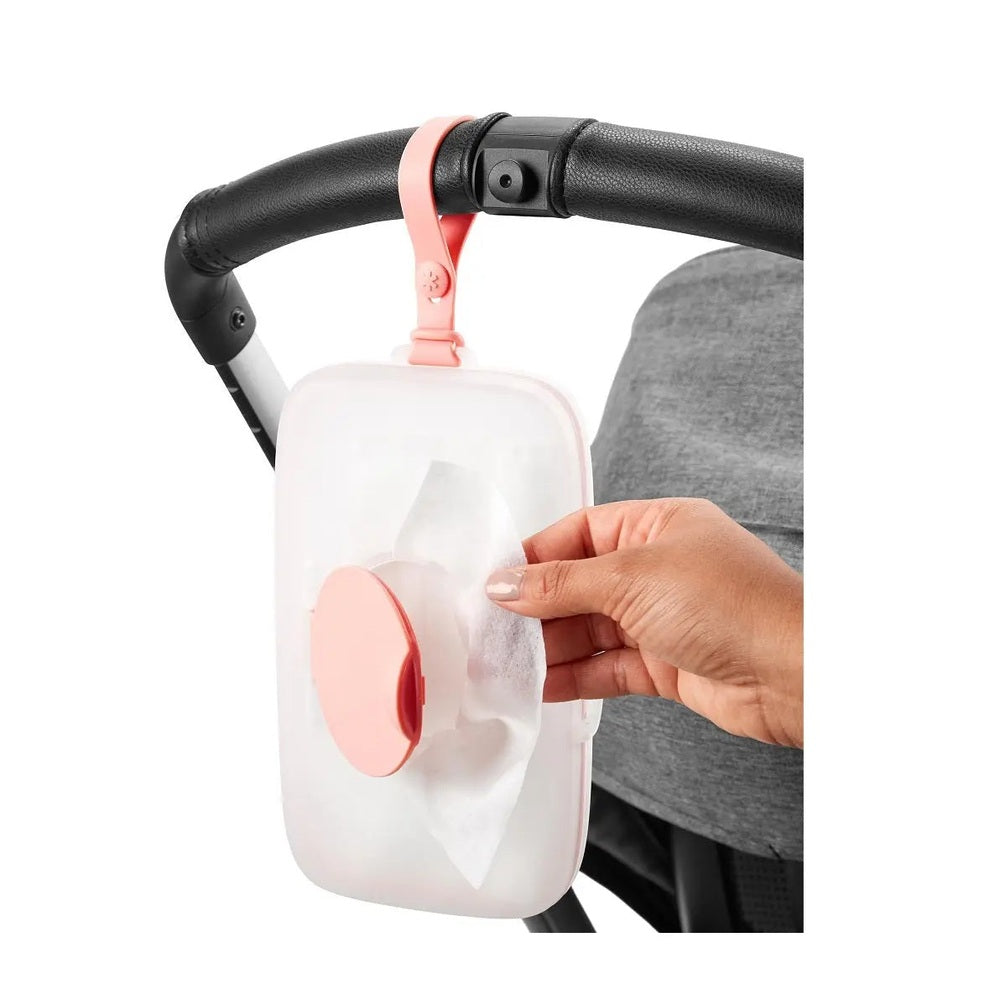 Skip Hop Grab & Go Snug Seal Wipes Case in pink attached to a stroller; hand pulls wipe from seal.