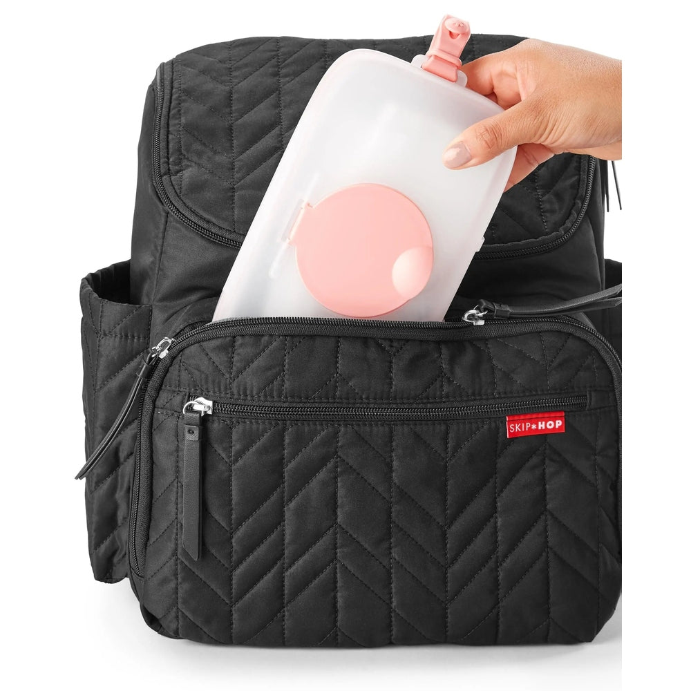 Skip Hop Grab & Go Snug Seal Wipes Case with pink lid being tucked into a black quilted diaper bag.