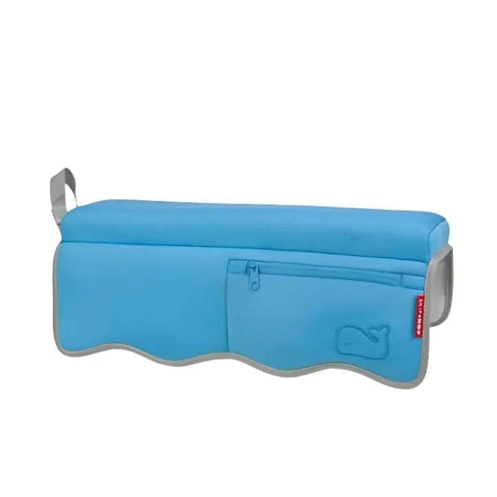 Skip Hop Moby Bathtub Elbow Rest blue cushioned bath pillow with zip pocket, secured along tub edge for elbow support.