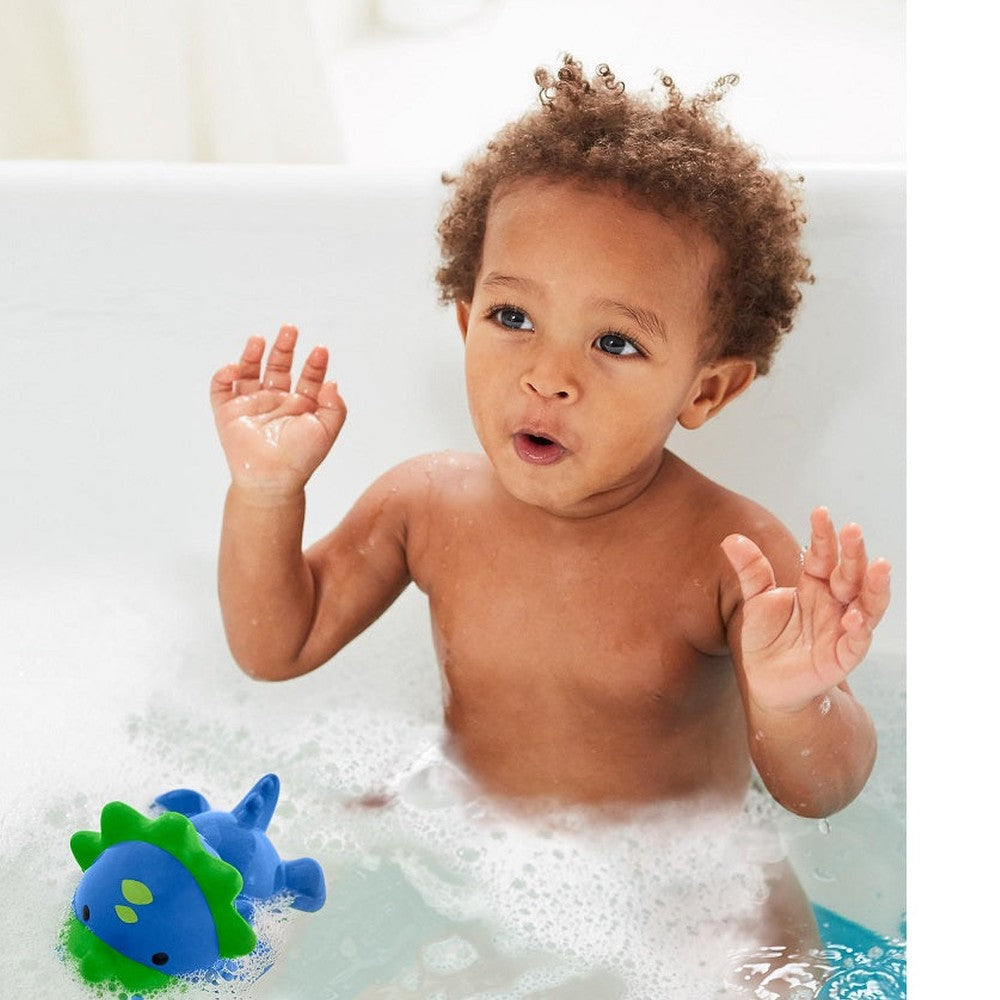 Skip Hop Zoo light-up bath toy dinosaur, blue with green fins, in bubbly bathtub