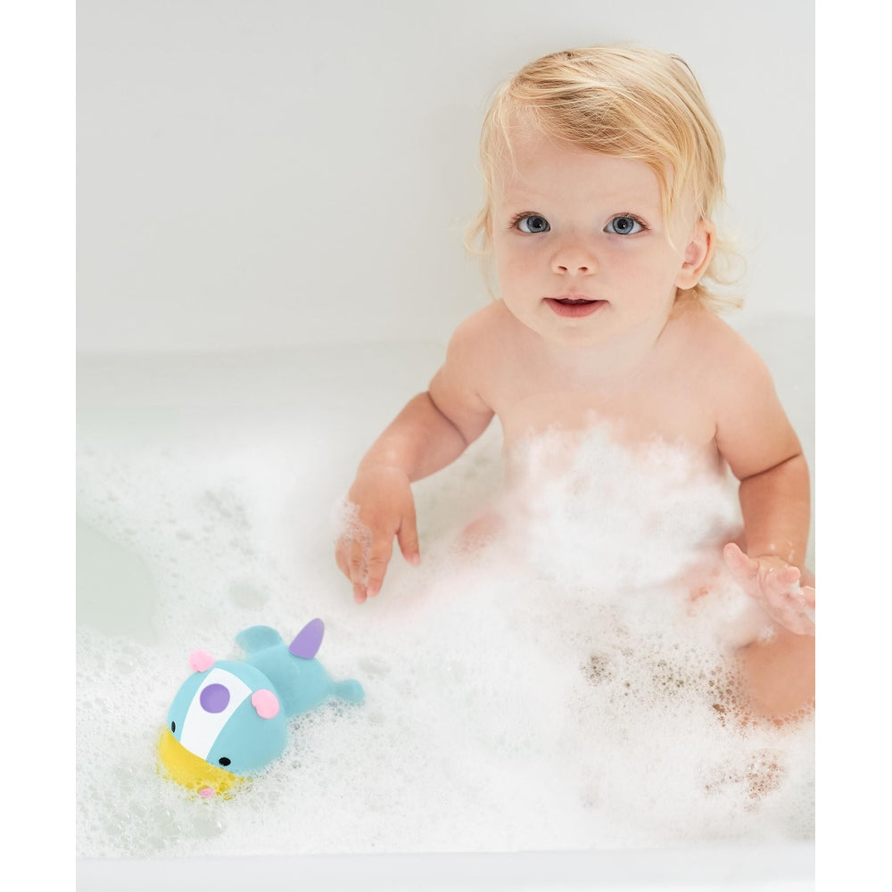 Skip Hop Zoo light-up bath toy unicorn, blue with yellow snout, in bubbly bath