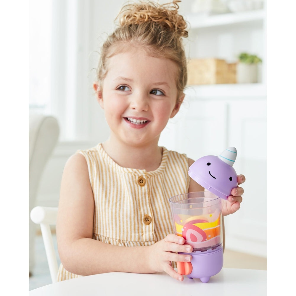Skip Hop Zoo Shake It Up Smoothie Set bottle with purple base and unicorn lid, held by a smiling child