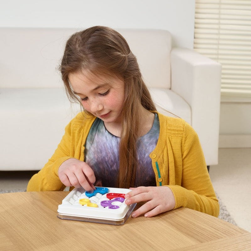 Smart Games Anti-Virus Mutation puzzle; girl in a yellow cardigan plays with colorful pieces on a tray.