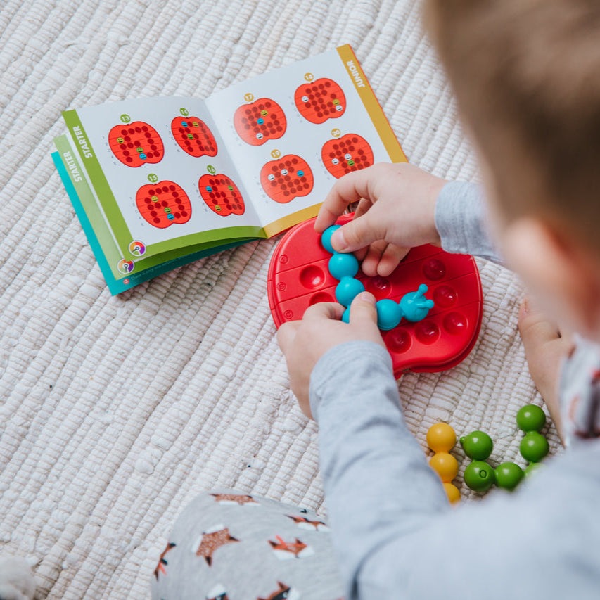 Smart Games Apple Twist puzzle, red circular board with blue interlocking pieces, educational toy for kids by SMART GAMES