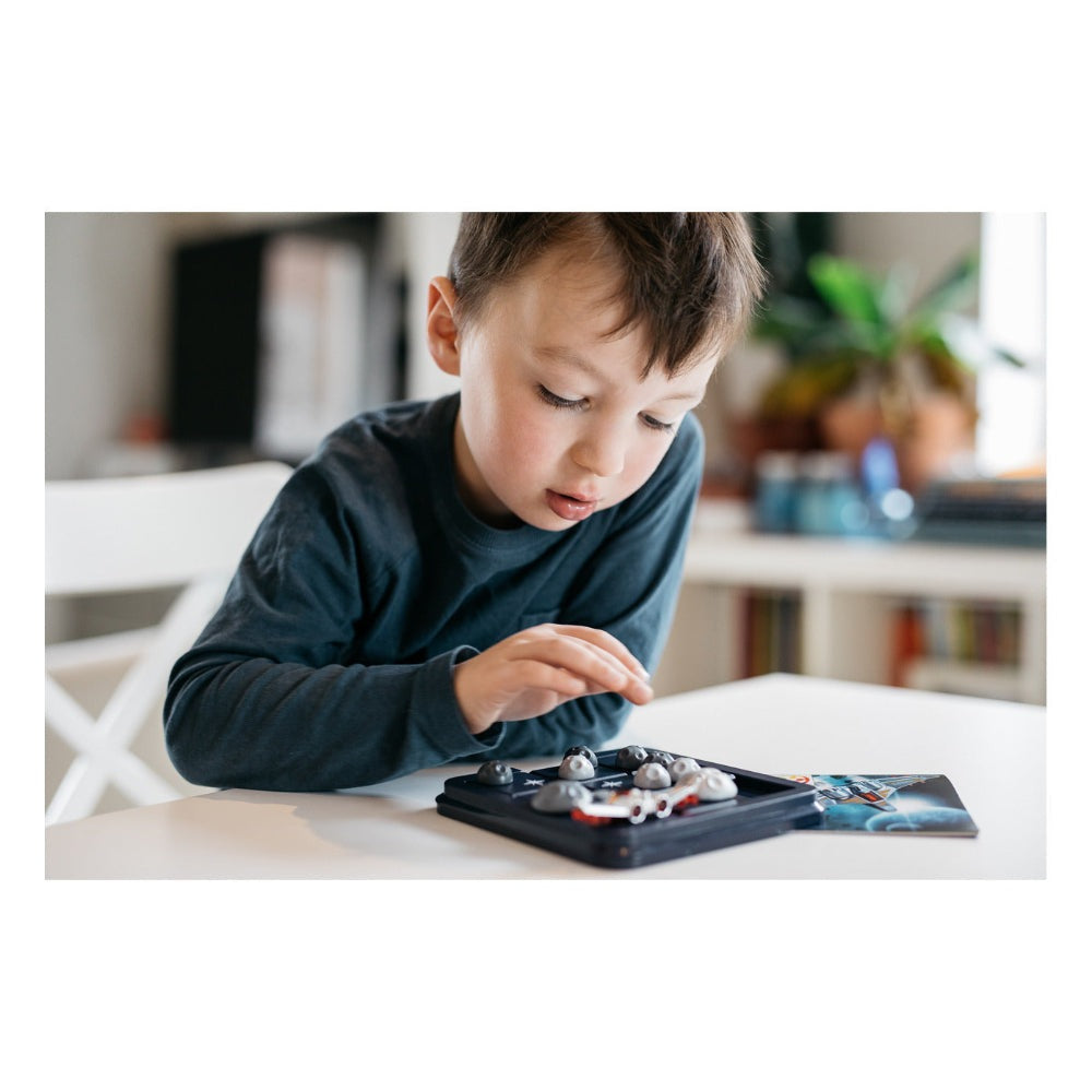 Smart Games Asteroid Escape puzzle game; boy engages with gray asteroid pieces on a black tray.
