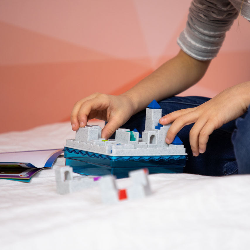 Smart Games Atlantis Escape toy set with gray castle blocks on a blue water base, child playing.