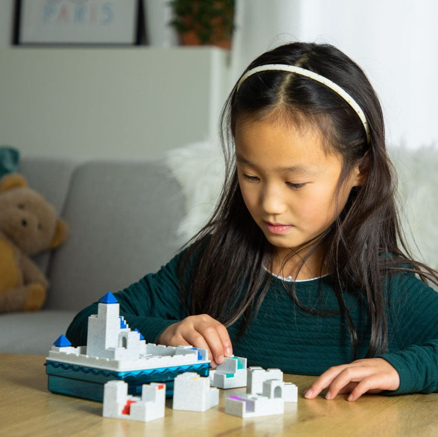 Smart Games Atlantis Escape puzzle set with white modular blocks and blue accents; child playing.