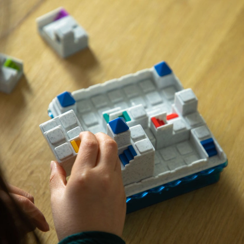 Smart Games Atlantis Escape puzzle board with white modular sections, blue base, and colorful blocks; child placing pieces