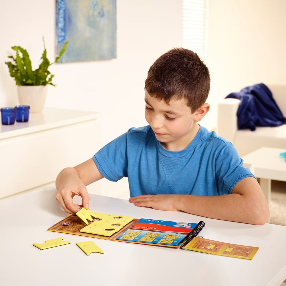 Smart Games Brain Cheeser educational puzzle set with yellow pieces and booklet being assembled by a boy