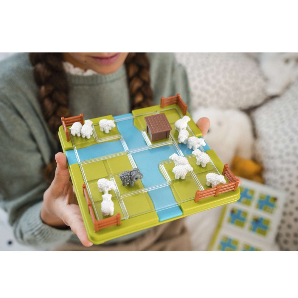 Smart Games Counting Sheep puzzle board with green grid, blue paths, white sheep, fences and a brown shed