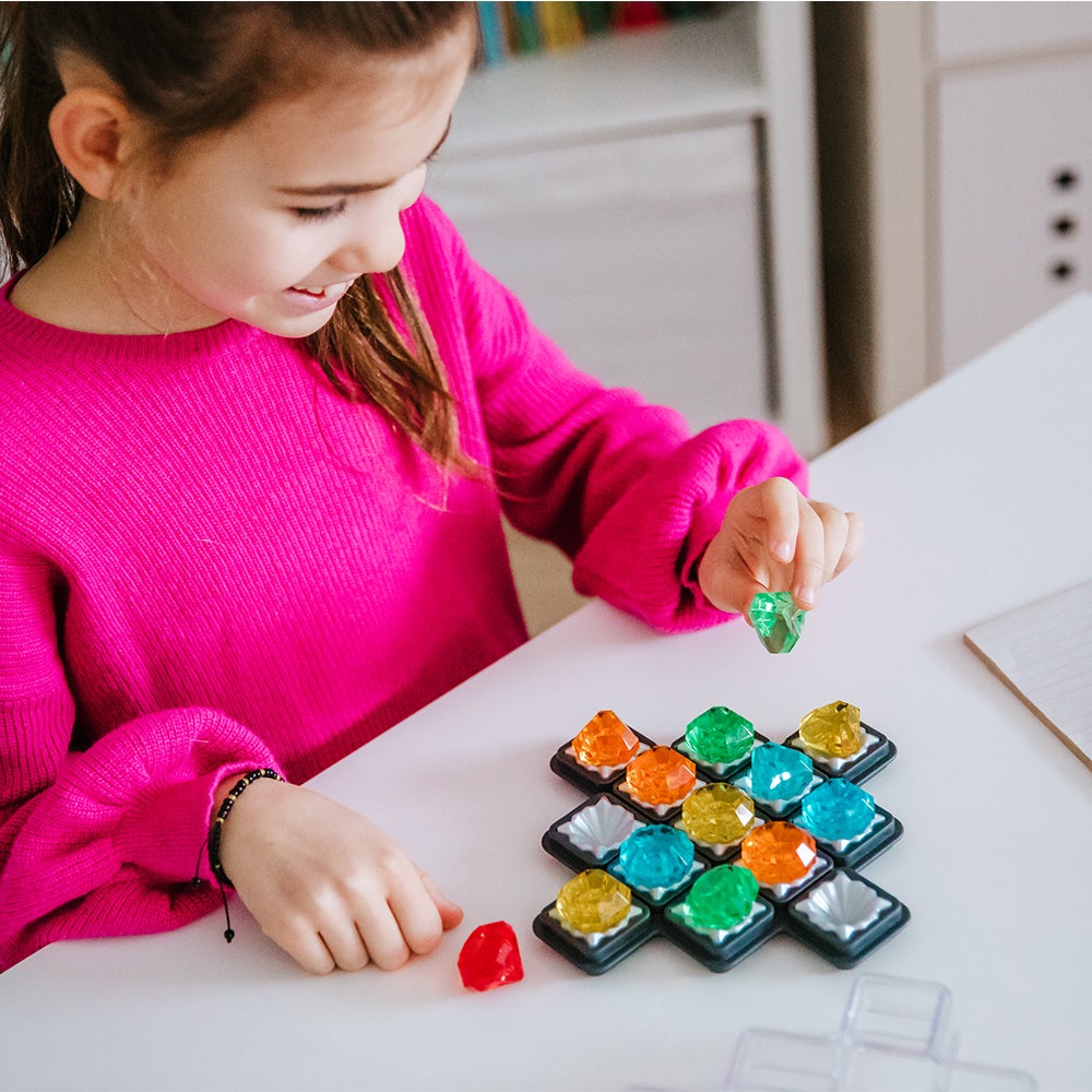 Smart Games Diamond Quest puzzle toy; child places bright multicolor gem diamonds on a grid.