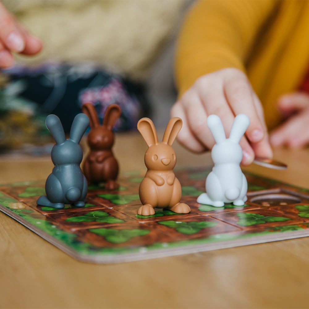 Smart Games Grabbit game with three bunny figures in blue-gray, brown and white on a colorful game board.