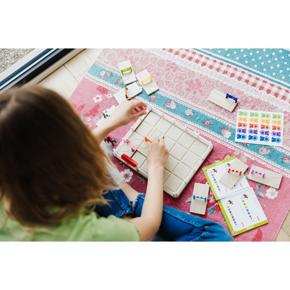 Smart Games Horse Academy puzzle; a child places colorful pegs on a grid, solving horse-themed logic clues.