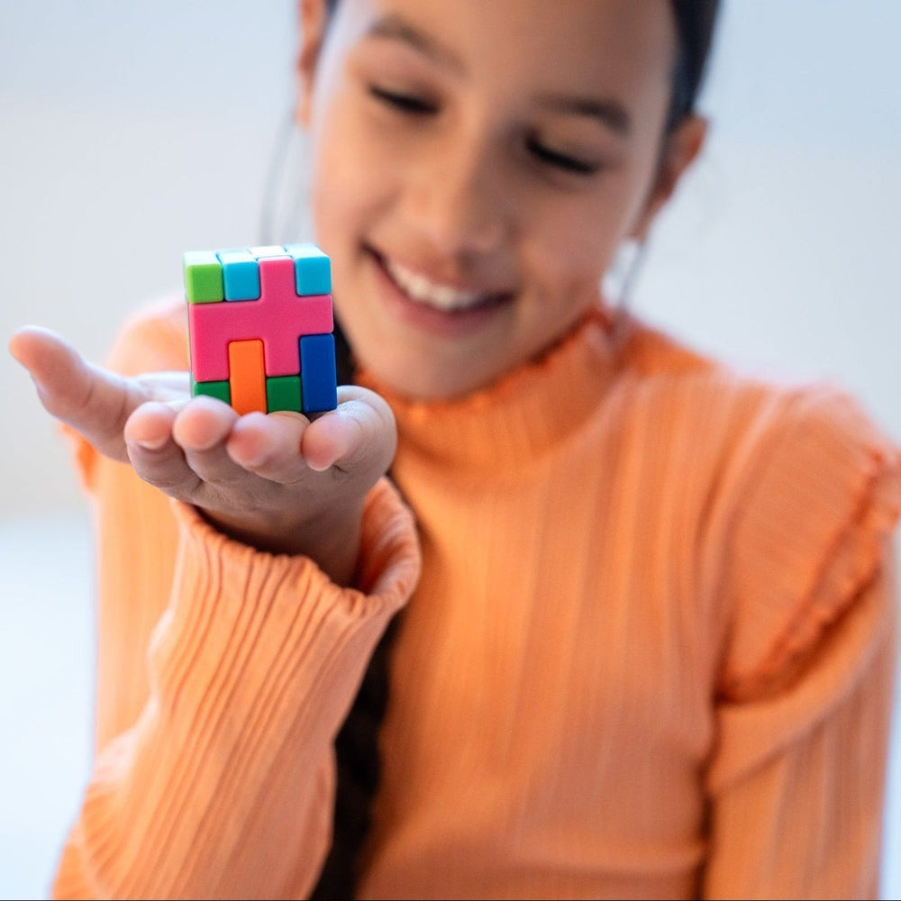 Child holding a colorful Rubik's cube in front of a blurred background