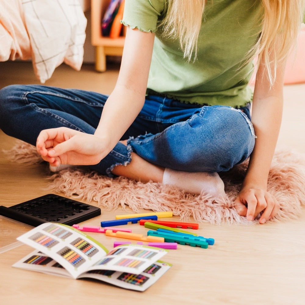 Smart Games IQ Stixx by SMART GAMES; colorful plastic sticks and instruction booklet on the floor.