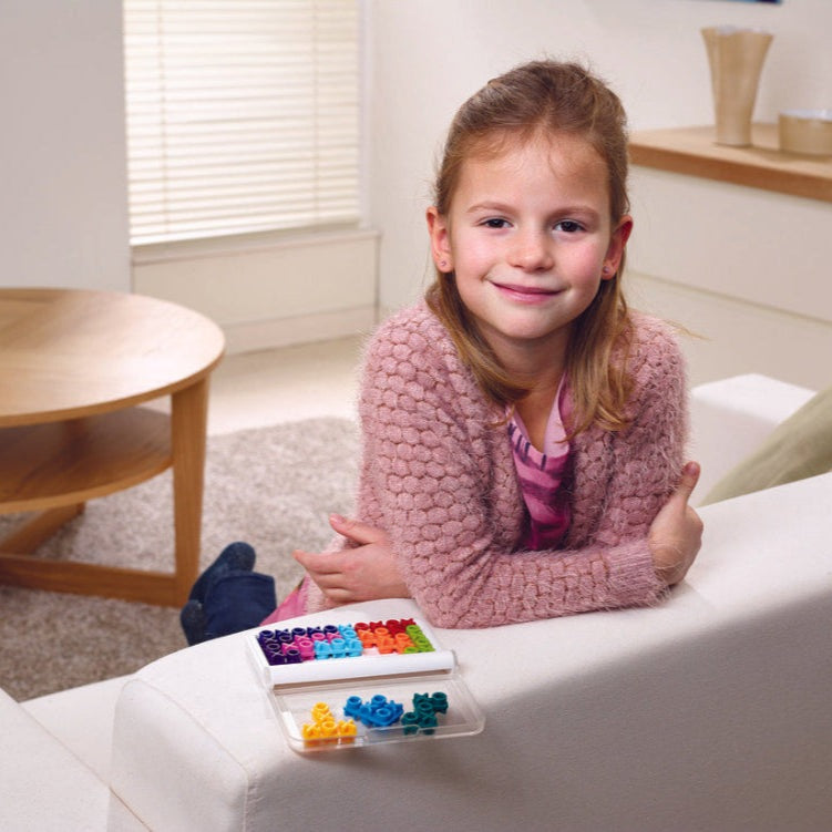 Smart Games IQ Xoxo puzzle by SMART GAMES; colorful letter blocks in a clear tray on a couch