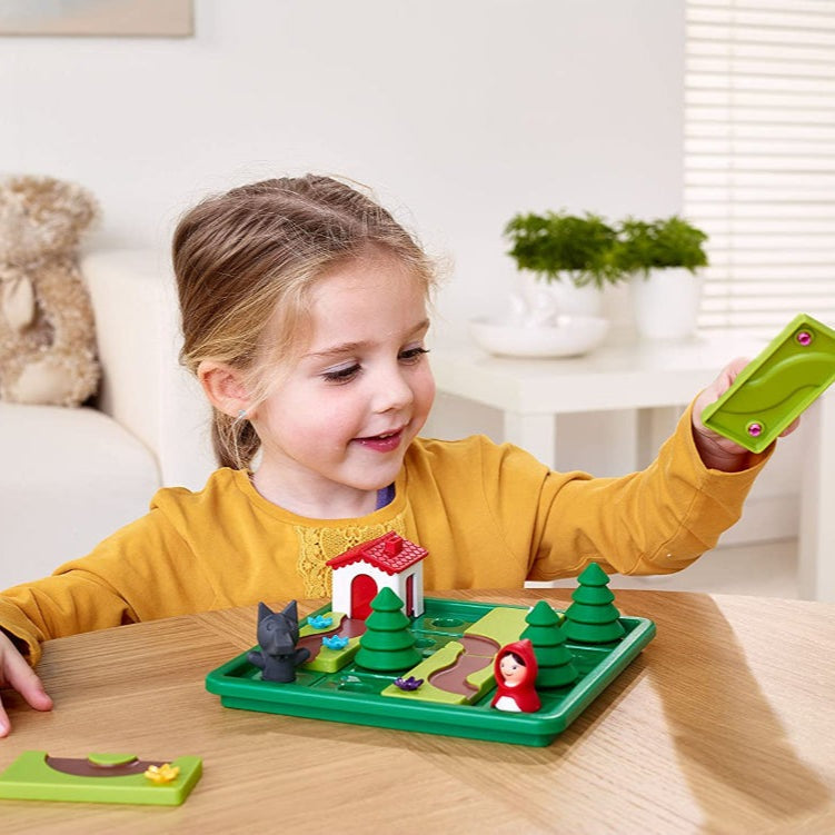 Smart Games Little Red Riding Hood Deluxe educational toy on a green board with trees, a small house, and red-hood figurine.