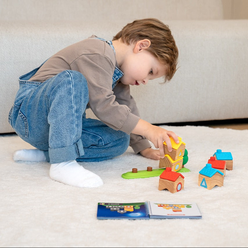 Child playing with colorful building blocks on a light-colored floor.