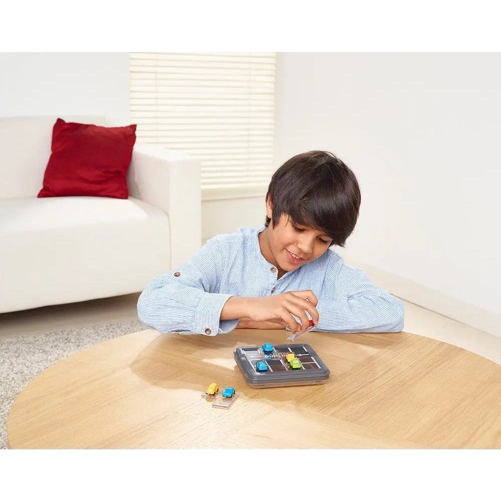 Smart Games Parking Tournis board game in a blue case, boy placing colorful tiles on a coffee table.