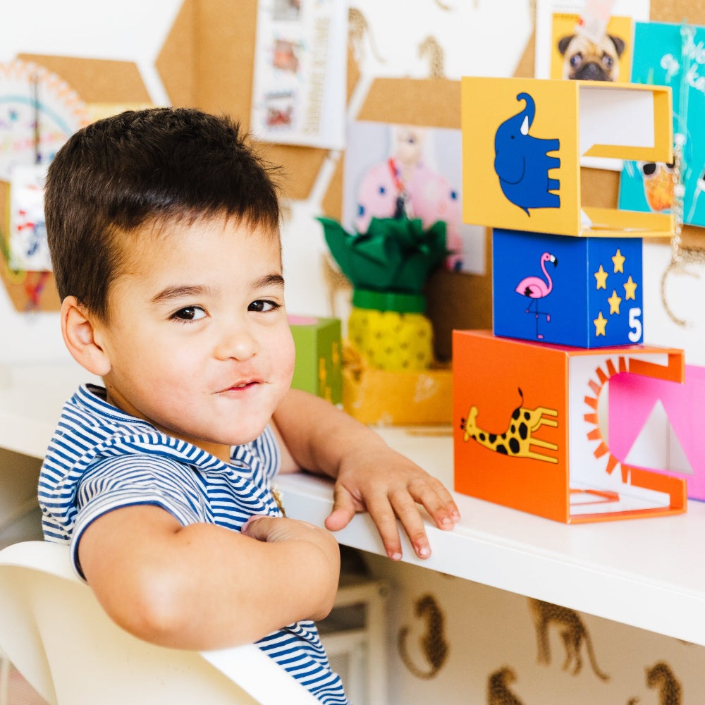 Smart Games Peek-A-Zoo blocks set with colorful animal illustrations; child playing.