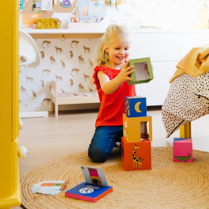 Smart Games Peek-A-Zoo wooden blocks stack game; colorful animal blocks and a child playing on a rug