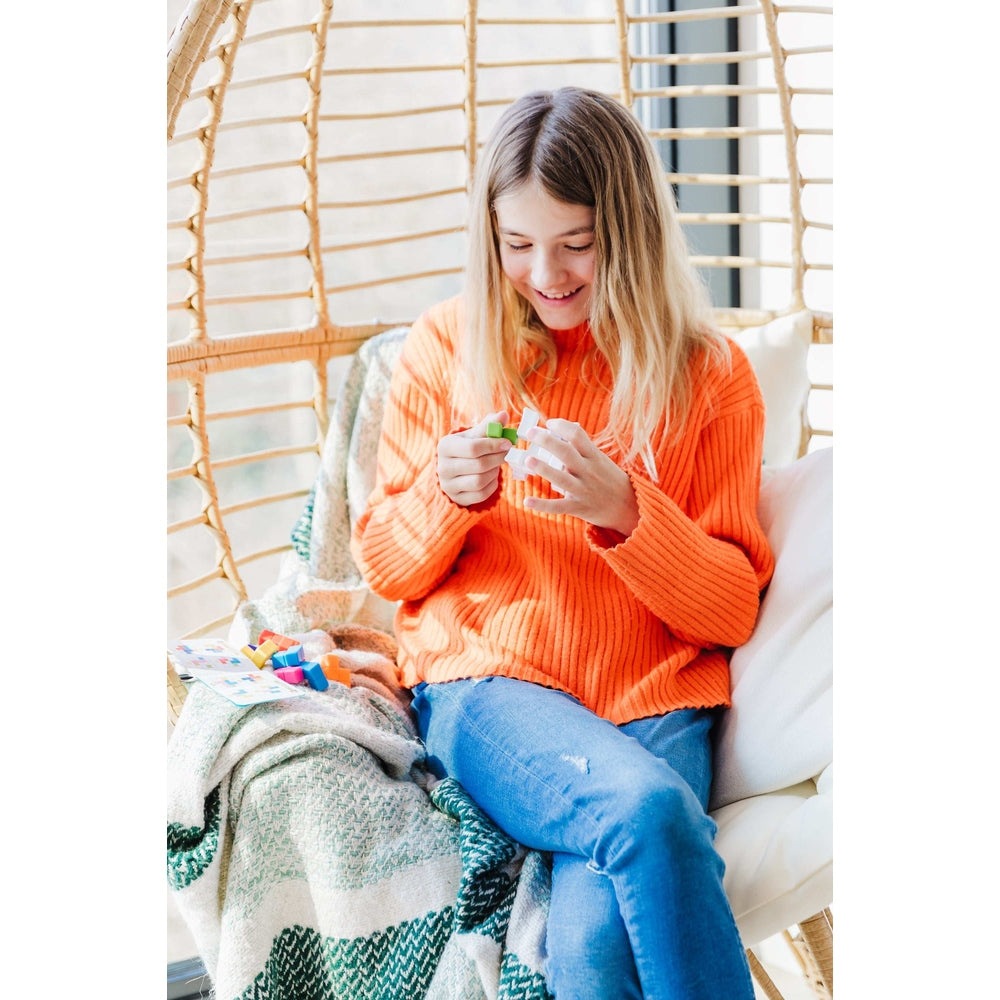 Smart Games Plug & Play Puzzler; girl in orange sweater playing with colorful blocks.