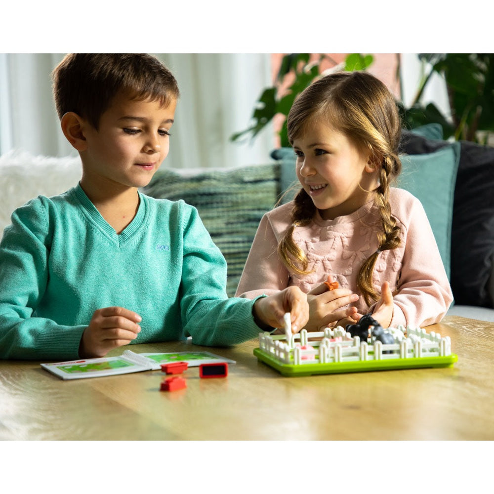Smart Games Smart Farmer board game for kids; two children play with a green farming board and small pieces